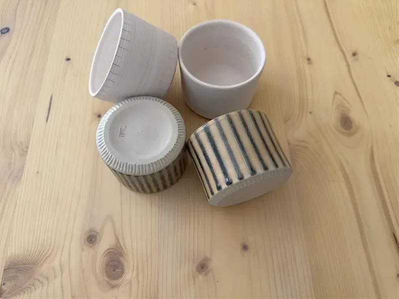 Vier Becher mit Streifen und eingeritzten Linien.